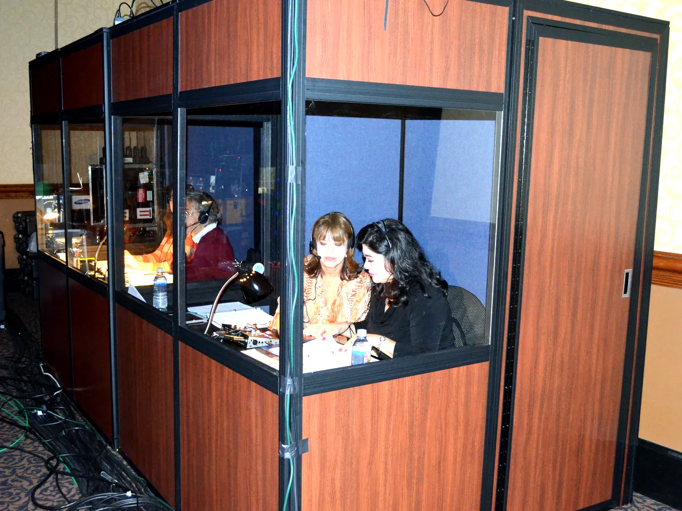 Intérpretes trabajando en una fila de cabinas de interpretación insonorizadas instaladas en el salón de un hotel