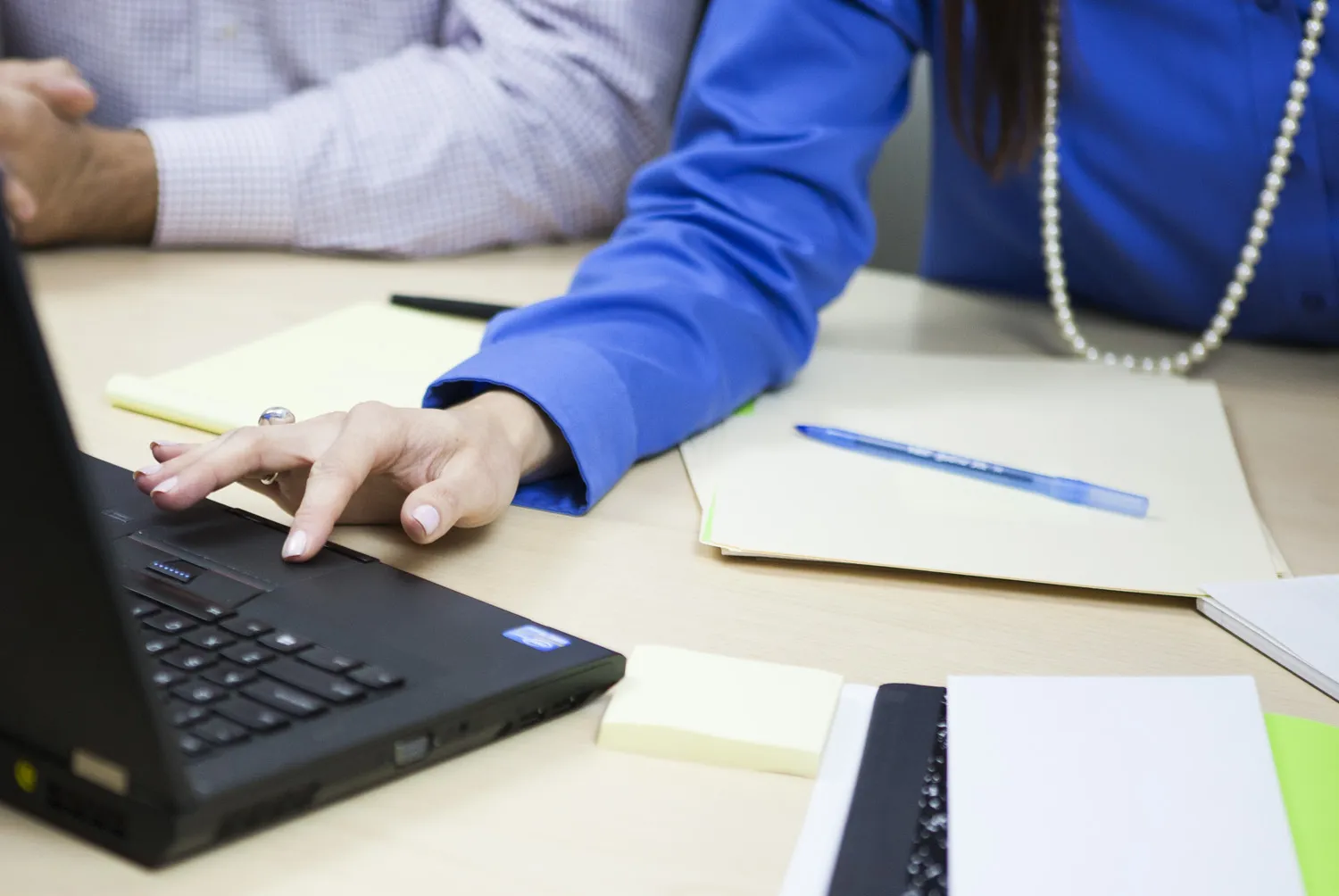 Una lingüista revisa un texto traducido en una laptop junto a borradores impresos