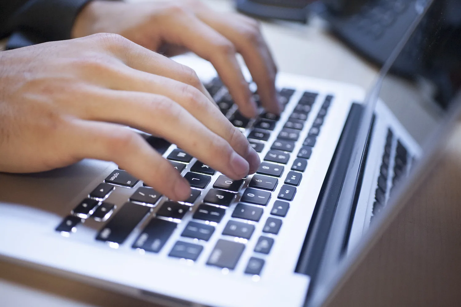 Las manos de una lingüista escriben una transcripción en una laptop